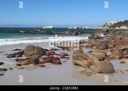 Malerisches türkisfarbenes Wasser im indischen Ozean entlang eines Sandstrandes mit großen Granitfelsen in der Nähe von Simons's Stadt auf der Kap-Halbinsel, Kapstadt, Südafrika Stockfoto