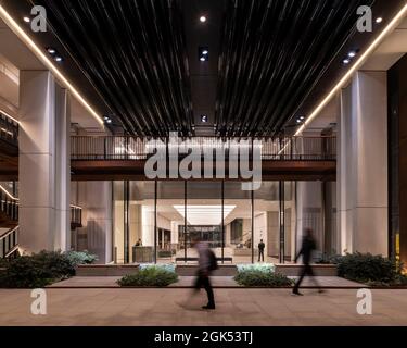 Blick zurück in die Lobby des Gebäudes von der überdachten Fußgängerstraße in der Nacht. London Wall Place, London, Großbritannien. Architekt: Make Ltd, 2019. Stockfoto