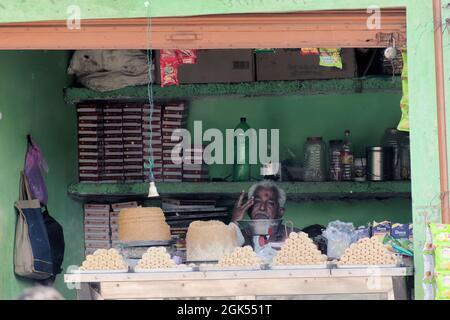 Orchha, Madhya Pradesh, Indien - 2019. März: Ein indischer Ladenbesitzer, der in seinem alten rustikalen Süßigenshop sitzt und traurig und besorgt aussieht. Stockfoto