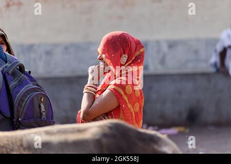 Orchha, Madhya Pradesh, Indien - März 2019: Ein ehrliches Porträt einer indischen Frau, die in einem traditionellen roten Sari mit einem Schleier gekleidet ist. Stockfoto