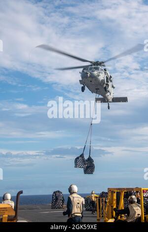 PAZIFIK (Aug 5, 2021) ein MH-60S Seahawk-Hubschrauber liefert während einer Auffüllung auf See mit dem Trockenfracht- und Munitionsschiff USNS Matthew Perry (T-AKE 9) Fracht auf dem Flugdeck des nach vorne eingesetzten amphibischen Sturmschiffes USS America (LHA 6). Amerika, das Flaggschiff der America Expeditionary Strike Group, und die 31. Marine Expeditionary Unit sind im Verantwortungsbereich der 7. Flotte der USA tätig, um die Interoperabilität mit Verbündeten und Partnern zu verbessern und als einsatzbereite Einsatztruppe für Frieden und Stabilität in der Indo-Pazifik-Region zu dienen. Stockfoto