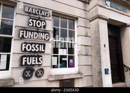 Graffiti, darunter das Logo der Extinction Rebellion, das auf einer Wand der Barclays Bank geschrieben wurde und gegen die Verwendung fossiler Brennstoffe protestiert, verursachen die globale Erwärmung und den Klimawandel. Lewes in East Sussex, Großbritannien. (127) Stockfoto