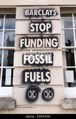 Graffiti, darunter das Logo der Extinction Rebellion, das auf einer Wand der Barclays Bank geschrieben wurde und gegen die Verwendung fossiler Brennstoffe protestiert, verursachen die globale Erwärmung und den Klimawandel. Lewes in East Sussex, Großbritannien. (127) Stockfoto