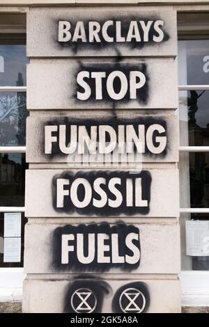 Graffiti, darunter das Logo der Extinction Rebellion, das auf einer Wand der Barclays Bank geschrieben wurde und gegen die Verwendung fossiler Brennstoffe protestiert, verursachen die globale Erwärmung und den Klimawandel. Lewes in East Sussex, Großbritannien. (127) Stockfoto