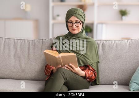 Glückliche Ältere Islamische Dame Liest Buch Mit Brille Zu Hause Stockfoto