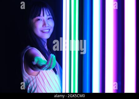 Junge asiatische Frau posieren mit bunten hellen Neonlichtern im Studio. Stockfoto