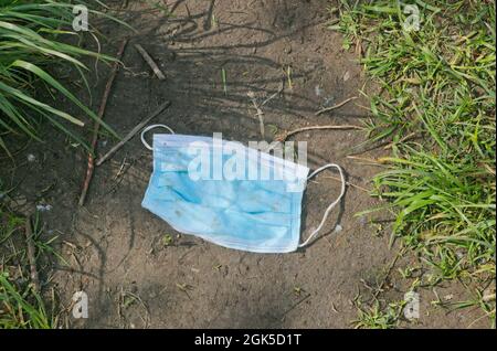 Gebrauchte chirurgische Maske auf dem Weg aufgegeben Stockfoto