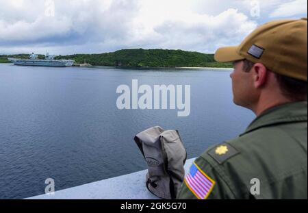 210807-N-MT581-1140 PAZIFISCHER OZEAN (AUG 7, 2021) Lt. Cmdr. Aaron Raper aus Washington, D.C., Planungs- und Taktikoffizier an Bord des Amphibientransportschiffes USS John P. Murtha (LPD 26), blickt auf den Flugzeugträger der britischen Royal Navy HMS Queen Elizabeth (R08) in der Hafenbasis Guam, August 7. John P. Murtha nimmt an der Übung Freedom Banner Teil, einer jährlichen Übung, die die strategische Projektion der Maritime Prepositioning Force (MPF) und der zugehörigen Kampftruppen beinhaltet. Die diesjährige Iteration unterstützt Large Scale Exercise (LSE) 2021, die darauf ausgelegt ist, die Synchronisationsführung zu verfeinern Stockfoto