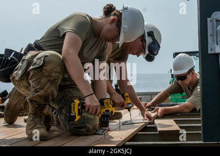 Pvt. First Class Jillian Ross, eine Fachkraft für Zimmerei und Mauerwerk bei der 185. Engineer Company, sichert sich im Rahmen der jährlichen Schulung ihrer Einheit am 9. August 2021 in Kittery die Terrasse mit einer elektrischen Bohrmaschine am nördlichen Pier von Wood Island. Die 185. Ingenieurgesellschaft arbeitete mit dem Wood Island Restoration Project zusammen, einem Komitee, das 2011 gegründet wurde, um Wood Island und die US-Rettungsstation wieder in ihr ursprüngliches und historisches Gesicht zu bringen. (Maine A Stockfoto