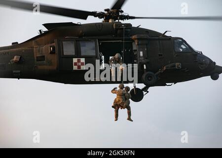 Am 9. August 2021 werden auf einem Jungle Penetrator, einem Werkzeug zur Gewinnung ambulanter Opfer aus stark bewaldeten Gebieten, im Baturaja Training Area, Indonesien, eine US-Army Flight Sanitäterin mit Diamantkopf der Task Force, ein 25th Aviation Regiment und ein US Army Combat Medic mit Task Force Warrior hochgehisst. Garuda Shield 21 ist eine zweiwöchige gemeinsame Übung zwischen der US-Armee und Tentara Nasional Indonesia (TNI-AD Indonesia Armed Forces). Der Zweck dieser gemeinsamen Übung ist es, die Dschungelkriegfähigkeit sowohl der US-Armee als auch der indonesischen Armee zu verbessern und zu bereichern. Stockfoto