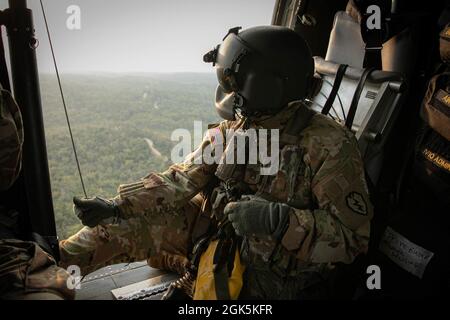 Ein Flug der US-Armee mit einem Diamantkopf der Task Force, 25. Luftfahrtregiment, blickt am 9. August 2021 aus einem HH-60 Blackhawk heraus, während er einen Jungle Penetrator hält, ein Werkzeug, mit dem ambulante Opfer aus stark bewaldeten Gebieten in Baturaja Training Area, Indonesien, extrahiert werden. Garuda Shield 21 ist eine zweiwöchige gemeinsame Übung zwischen der US-Armee und Tentara Nasional Indonesia (TNI-AD Indonesia Armed Forces). Der Zweck dieser gemeinsamen Übung ist es, die Dschungelkriegfähigkeit sowohl der US-Armee als auch der indonesischen Armee zu verbessern und zu bereichern. Stockfoto