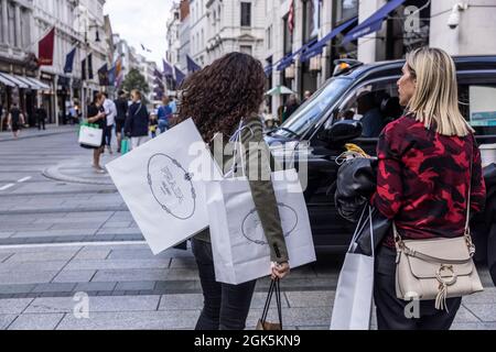 Käufer von Luxusmarken, die PRADA-Taschen in der Old Bond Street, London, England, Großbritannien, tragen Stockfoto