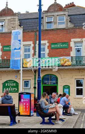 Urlauber, die Fisch und Chips vor dem Parade Fish and Chip Restaurant im The Square, Swanage Dorset England, Großbritannien, genießen Stockfoto