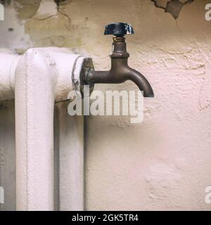 Wasserhahn zum Ablassen von Wasser auf einer alten gusseisernen Dampfheizung Batterie Stockfoto