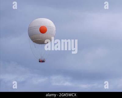 Ein wunderschöner weißer Heißluftballon fliegt am bewölkten Himmel ohne Menschen an Bord Stockfoto