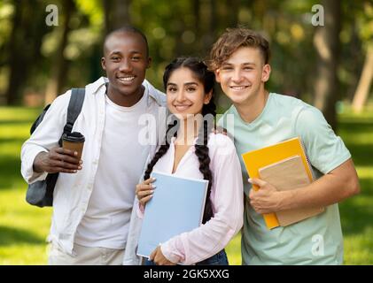 Glückliche internationale Universitätsstudenten, die nach dem Unterricht Pause machen und mit Notebooks im Freien auf dem Campus posieren Stockfoto