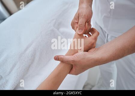 Massotherapeutin, die einer weiblichen Klientin eine Handmassage gibt Stockfoto