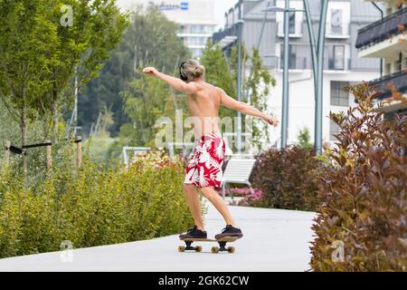 Blonde junge Mann Skateboarding im Park Stockfoto