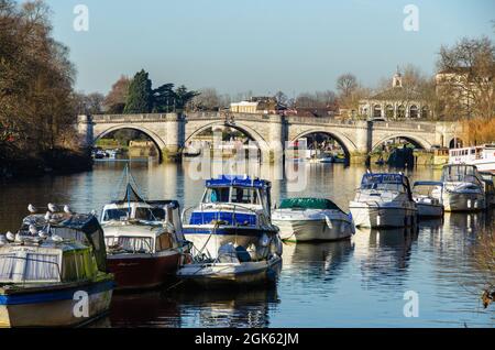 Vergnügungsboote, die auf der Themse mit der Richmond Bridge im Hintergrund, Richmond-upon-Thames, Surrey, England, festgemacht haben Stockfoto
