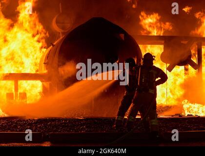 Feuerwehrleute der lettischen Bundeswehr und der estnischen Streitkräfte löschen mit einem Schlauch einen simulierten Flugzeugbrand im Alpena Combat Readiness Training Center, Michigan, 12. August 2021. Die Simulation war Teil von Northern Strike 21-2, einer von der Nationalgarde gesponserten Übung, die ein maßgeschneiderter Bereitschaftsproduzent ist, der 5,100 Teilnehmer aus verschiedenen Staaten und Ländern im National All-Domain Warfighting Center zusammengebracht hat. Stockfoto