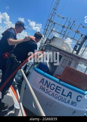 Ein 45-Fuß-Reaktionsboot der Küstenwache in St. Petersburg – die mittlere Besatzung sprüht Wasser über ein 60-Fuß-Schiff, das östlich der Skyway-Brücke in Brand gesetzt wird, am 13. August 2021. Die beiden Männer an Bord des Schiffes wurden ohne Verletzungen sicher in O'Neill’s Marina zum wartenden Rettungsdienst gebracht. Stockfoto