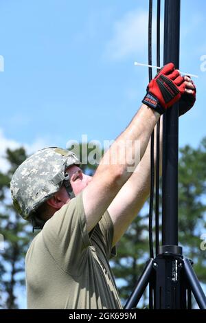 Brian Abert, Senior Airman, ein Flugtechniker des 104. Kampfflügels, sichert sich während der Einrichtung einer Antenne für die Kommunikation am Standort eines gemeinsamen Vorfalls einen Draht, um neue Teammitglieder am 13. August 2021 auf der Barnes Air National Guard Base, Massachusetts, auszubilden. Die JISCC-Antenne wird für die Unterstützung von Cross-Band-Landfunkgeräten, für die Versorgung von Punkt-zu-Punkt-WLAN, taktischem Boden-Luft-Radar und Client-WLAN verwendet. Stockfoto