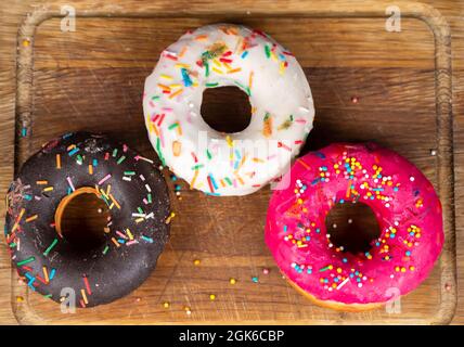 Wunderschönes, süßes Essen. Stapel von glasierten bunten verschiedenen Donuts auf einem hölzernen Hintergrund. Stockfoto