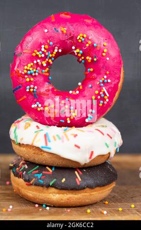 Schönes, süßes Essen. Stapel von glasierten bunten verschiedenen Donuts mit Spritzern auf einem grauen Hintergrund. Stockfoto