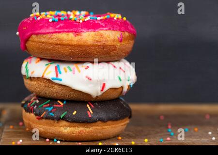 Schönes, süßes Essen. Stapel von glasierten bunten verschiedenen Donuts mit Spritzern auf einem grauen Hintergrund. Stockfoto