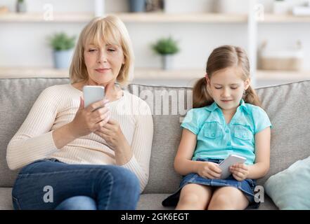 Reife Frau und Enkelin mit Mobiltelefonen Stockfoto