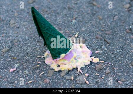 Helles Eis in einem grünen Kegel fiel auf den Asphalt. Seitenansicht. Nahaufnahme. Stockfoto