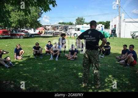 US Marine Maj. Brian Hubert, Mitte, der Kommandant der Recruiting Station (RS) Cleveland beantwortet Fragen von Poolees mit RS Cleveland auf der Cuyahoga County Fair in Middleburg Heights, Ohio, 14. August 2021. Ziel der Veranstaltung war es, dass sich Rekrutierer mit der lokalen Gemeinschaft auseinandersetzen und Zivilisten zur Teilnahme an einer Pull-up-Herausforderung einladen, um die Preise des Marine Corps zu erhalten. Stockfoto