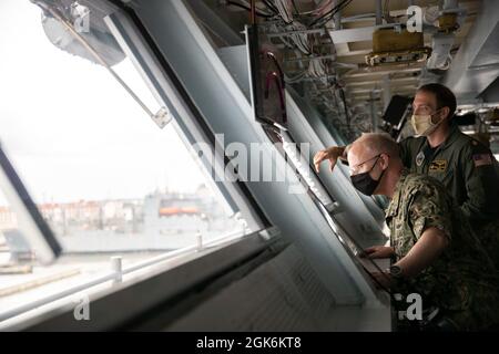 Vice Adm. Daryl Caudle, Kommandant der Submarine Forces (SUBFOR), links, erhält einen Brief von LT. Cmdr. Greg Sutter, aus Orlando, USS Gerald R. Fords (CVN 78) Assistenznavigator, in Fords Pilothaus während einer Schiffstour am 16. August 2021. Caudle besuchte Ford mit ausgewählten SUBFOR- und US-amerikanischen Mitarbeitern der zweiten Flotte, um sich einen Einblick in die Materialbereitschaft des Schiffes nach den historischen Full Ship Shock Trials (FSST) von Ford zu verschaffen. Die US Navy führt Schockversuche an neuen Schiffsdesigns mit Live-Sprengstoffen durch, um zu bestätigen, dass unsere Kriegsschiffe weiterhin die anspruchsvollen Missionsanforderungen erfüllen können un Stockfoto