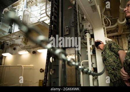 Vice Adm. Daryl Caudle, Commander, Submarine Forces (SUBFOR), sieht zu, wie einer der fortschrittlichen Waffenaufzüge der USS Gerald R. Ford (CVN 78) während einer Schiffsrundfahrt am 16. August 2021 inerte Ordnance auf Ford's Flugdeck bringt. Caudle besuchte Ford mit ausgewählten SUBFOR- und US-amerikanischen Mitarbeitern der zweiten Flotte, um sich einen Einblick in die Materialbereitschaft des Schiffes nach den historischen Full Ship Shock Trials (FSST) von Ford zu verschaffen. Die US-Marine führt Schockversuche an neuen Schiffsdesigns mit Live-Sprengstoffen durch, um zu bestätigen, dass unsere Kriegsschiffe auch unter den harten Bedingungen weiterhin anspruchsvolle Missionsanforderungen erfüllen können Stockfoto