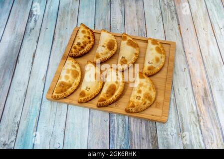 Acht argentinische Empanadas verschiedener Geschmacksrichtungen, bereit für einen Snack auf Bambusholzbrett Stockfoto