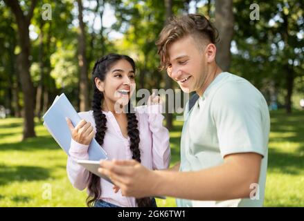 Nach der Untersuchung. Begeistert internationale Studenten Freunde feiern erfolgreichen Test Pass, Blick auf Lehrbuch und lächelnd Stockfoto