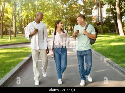 Drei multirassische High-School-Studenten gehen nach dem Studium und sprechen auf dem Universitätscampus im Freien Stockfoto