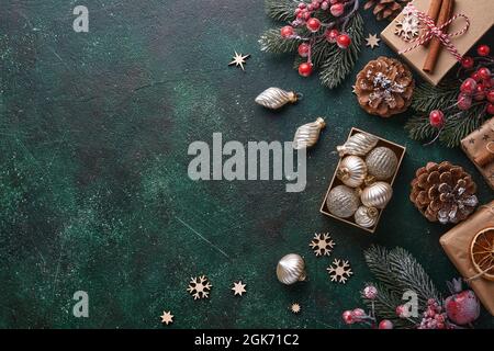 Weihnachtstanne Äste, Weihnachtskugeln, Geschenkbox, hölzerne Schneeflocken und Sterne auf grünem Betonstein Hintergrund für Ihre Weihnachtsgrüße. Oben vi Stockfoto