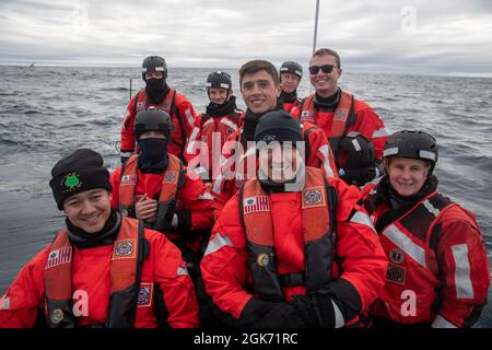 LABRADOR SEA -- (Aug 19, 2021) Mitglieder der USCGC Escanaba (WMEC 907) machen auf einem kleinen Cutter-Boot in der Labradorsee ein Gruppenfoto. Die Escanaba ist ein 270 Meter langer, berühmter Mittelausdauerschneider mit einer Besatzung von rund 100 Personen und führt Missionen mit Schwerpunkt auf maritimer Sicherheit und Strafverfolgung durch Stockfoto