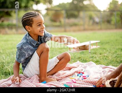 Glücklicher Junge, der im Park mit dem Flugzeug spielt Stockfoto