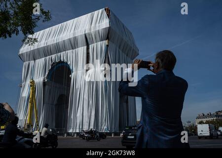 Paris, Frankreich. September 2021. Ein Besucher macht das Foto des eingewickelten Arc de Triomph in Paris. Der Triumphbogen wurde am 12. September gewickelt, um dem verstorbenen Künstler Christo zu Tribut zu zollen, der den Bogen vor seinem Tod in eine Packung wickeln wollte. Arbeiter wickelten es in einen recycelbaren und blauen Kunststoff und Band es mit einem roten Seil, wie Christo in seinem Projekt erwähnte. (Bild: © Abhijeet Gurjar/ZUMA Press Wire) Bild: ZUMA Press, Inc./Alamy Live News Stockfoto