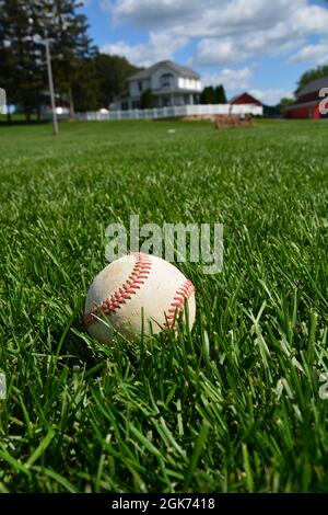 Ein Baseballspiel sitzt im Außenfeld des ehemaligen Filmset von Field of Dreams in Dyersville, Iowa. Der Fokus liegt auf dem Baseballspiel. Stockfoto