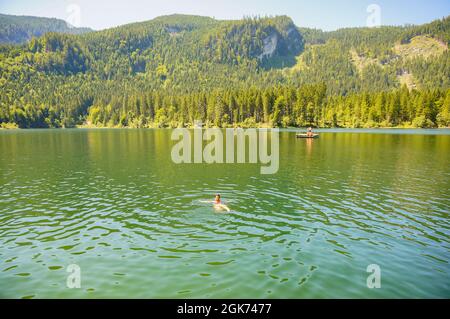 BAD MITTERNDORF, ÖSTERREICH - 24. Jul 2019: Blick auf eine Frau, die im wunderschönen Oedensee auf bewaldeten Hügeln schwimmend ist Stockfoto