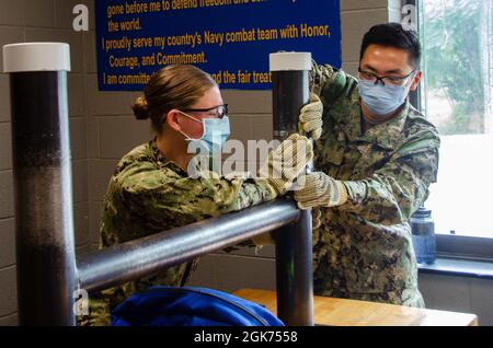 Midshipmänner, die dem NROTC-Programm (Naval Reserve Officers' Training Corps) der Yale University zugewiesen wurden, erhalten am 20. August 2021 an Bord des Naval Submarine Base New London Unterricht im Klassenzimmer sowie praktische Übungen im Naval Submarine School Damage Control Wet Trainer. Der Trainer soll U-Boot-Seeleuten bei der Vorbereitung auf Einsätze unterstützen, indem er Überschwemmungen in einer kontrollierten Umgebung simuliert. Stockfoto