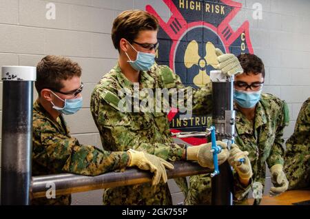 Midshipmänner, die dem NROTC-Programm (Naval Reserve Officers' Training Corps) der Yale University zugewiesen wurden, erhalten am 20. August 2021 an Bord des Naval Submarine Base New London Unterricht im Klassenzimmer sowie praktische Übungen im Naval Submarine School Damage Control Wet Trainer. Der Trainer soll U-Boot-Seeleuten bei der Vorbereitung auf Einsätze unterstützen, indem er Überschwemmungen in einer kontrollierten Umgebung simuliert. Stockfoto