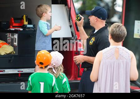 Duane White, mit der 788. Civil Engineer Squadron Fire Department, zeigt die dreijährige Noah Farnsworth während einer praktischen Ausstellung außerhalb des Day Air Credit Union Ballpark im Rahmen der Dayton Dragons Hometown Heroes Night Events, 21. August 2021, in Dayton, Ohio, wie ihre Radios funktionieren. Neben den Ausstellungen warfen die Militärs auch die zeremonielle erste Tonhöhe heraus, sangen die Nationalhymne und präsentierten die Farben während der Zeremonien vor dem Spiel. Stockfoto