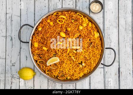 Bild von oben mit Fischfidua mit Tintenfisch, Muscheln, Aioli-Sauce und Zitrone auf weißem Tisch Stockfoto