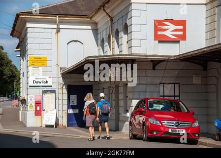 Dawlish, Devon, England, Großbritannien. 2021. Dawlish Badeort Bahnhof Gebäude, eine Außenansicht mit geparktem Auto und Passagiere. Stockfoto