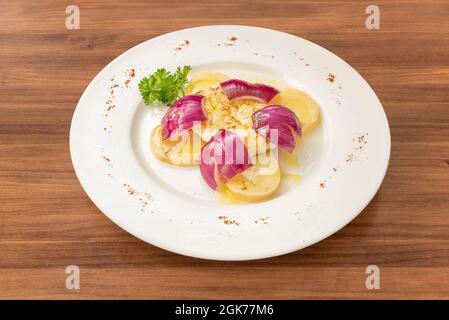 Spanisches Rezept für gegrillten Kabeljau mit gekochten Kartoffeln und roten Zwiebeln mit Olivenöl und frischer Petersilie Stockfoto