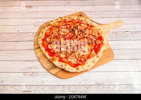 Großer italienischer Koch Zubereitung von Pizza mit dünner Kruste mit Barbecue-Sauce mit gehacktem gebratenem Huhn, Schinkenscheiben geschmortes Hackfleisch auf Holzbrett Stockfoto